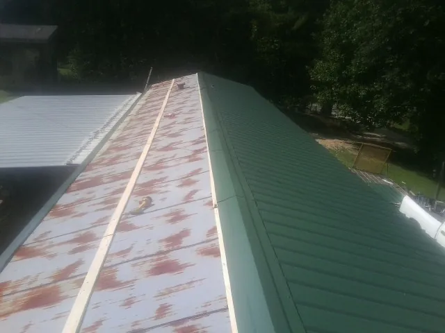 Old rusted panels beside newly installed green metal roofing — Wind Damage Roof Repair by Roofing Brothers in Port Richey