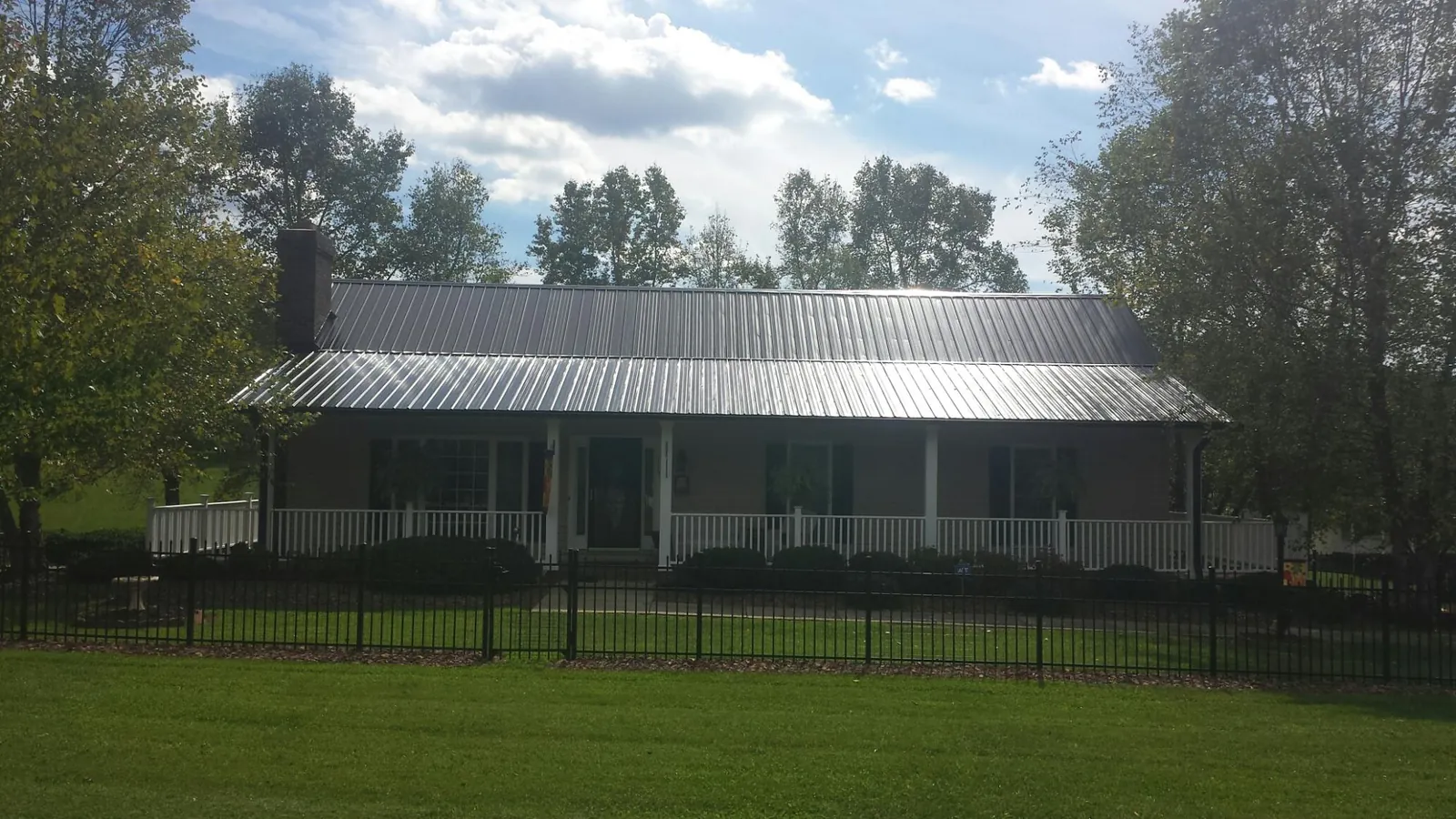 Gray metal roof on a brick ranch with a full width front porch — Gutter Guard Installation work by our crew in Port Richey