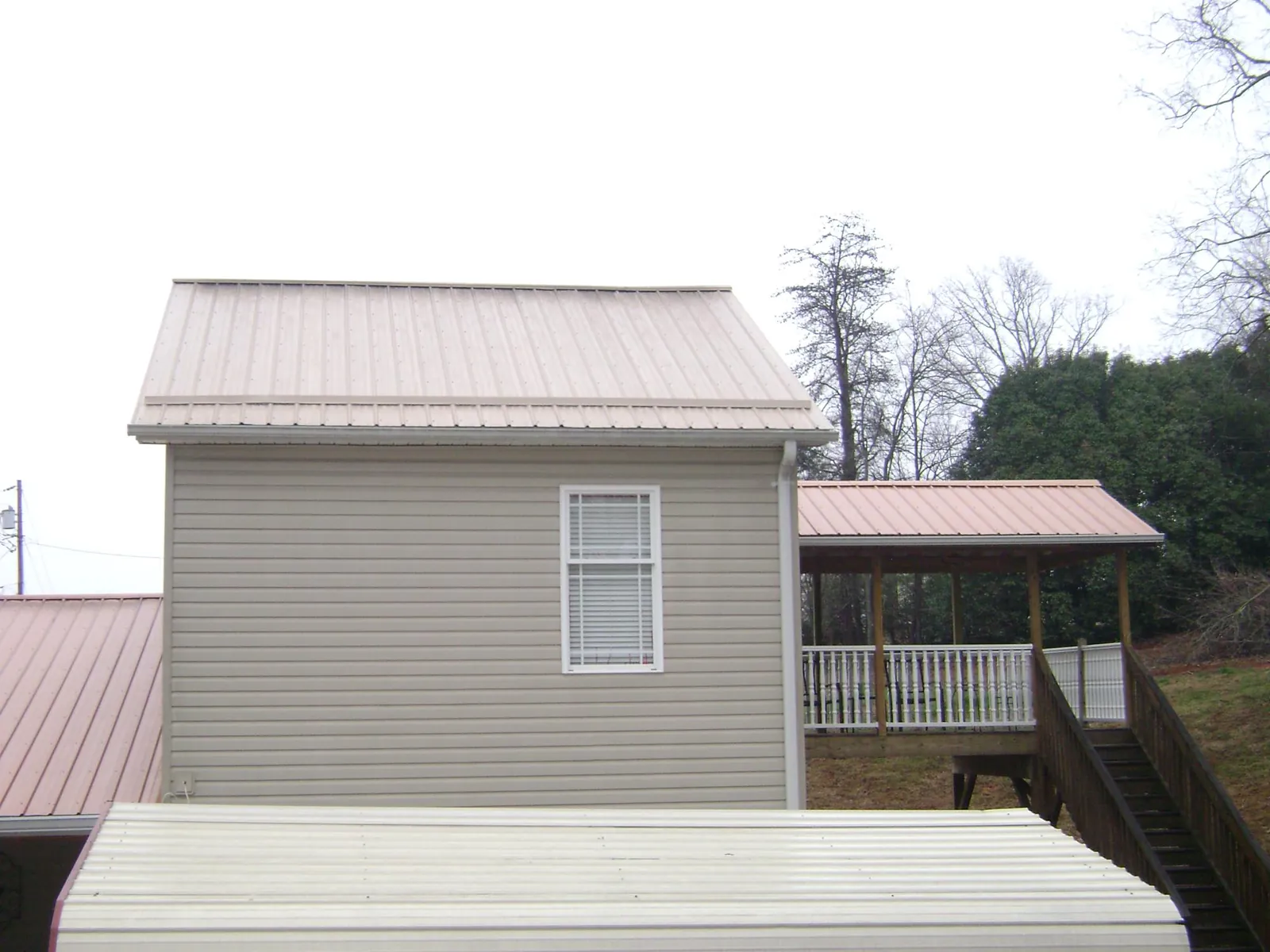 Tan metal roofs on a two story addition and attached porch, from a Roof Replacement job in Port Richey