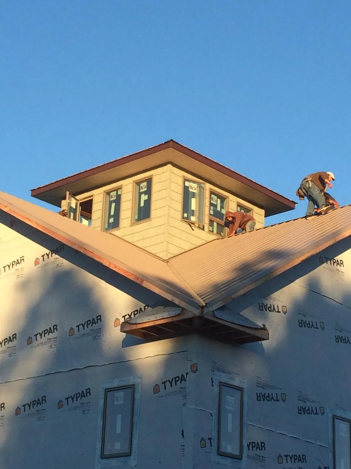 Roofers working around a rooftop cupola on a new metal roof at sunset — Roof Waterproofing in Port Richey by Roofing Brothers